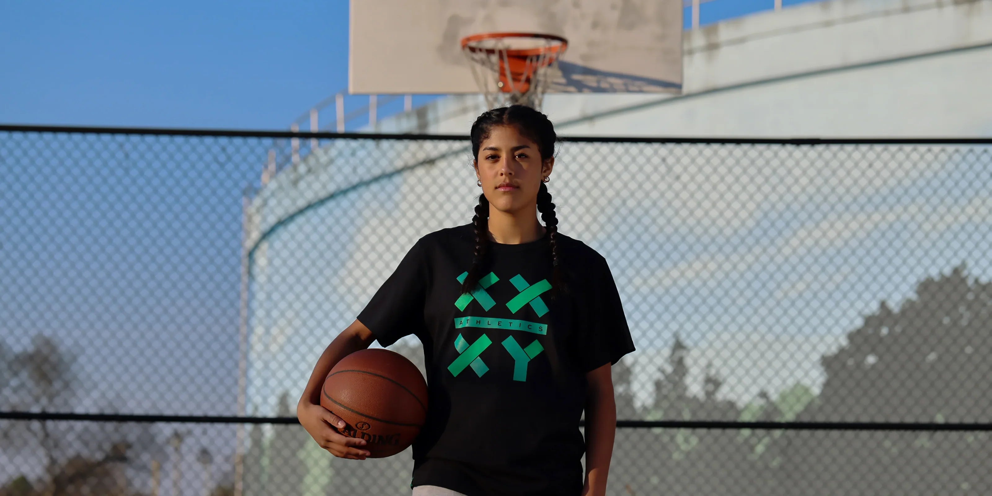 Girl wearing XX-XY Logo Tee in black while holding a basketball.