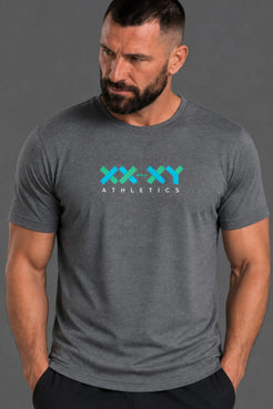 A muscular man wearing a dark heather gray t-shirt with a 'XX-XY ATHLETICS' graphic in teal and white on the chest, posed against a solid gray background. || Dark Heather Gray