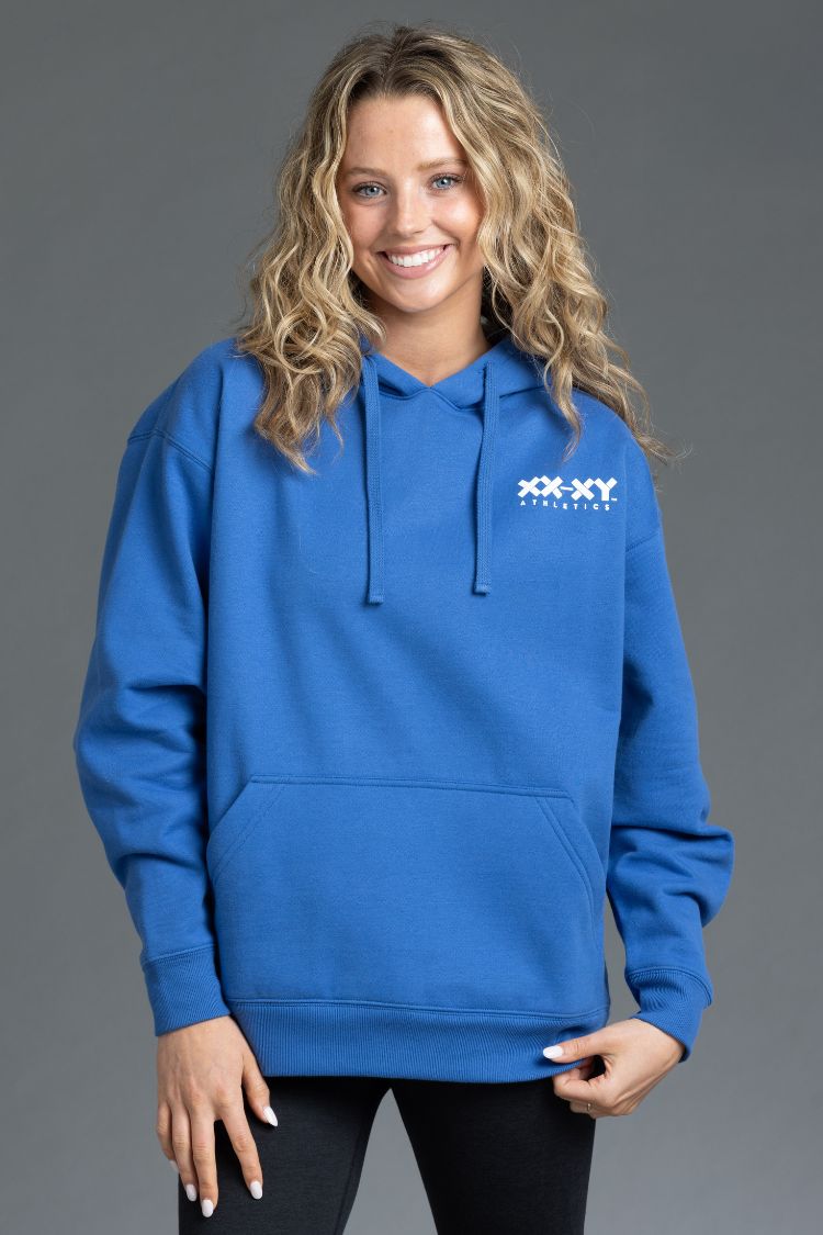 Woman wearing a blue hoodie with a logo on a gray background || Blue