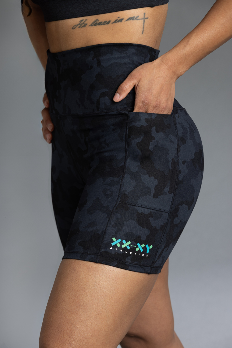 Black camouflage athletic shorts with a brand logo on a gray background