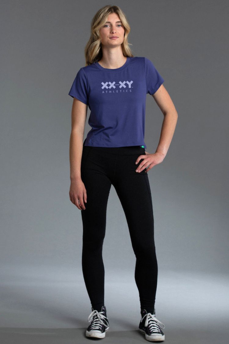 Woman wearing Blue t-shirt with a logo and black leggings || Indigo