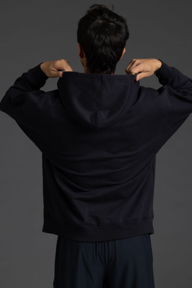 Person wearing a black hoodie and pants against a dark background || Black with Color Logo