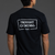 Person wearing a black t-shirt with 'THOUGHT CRIMINAL' text on the back against a gray background || Black