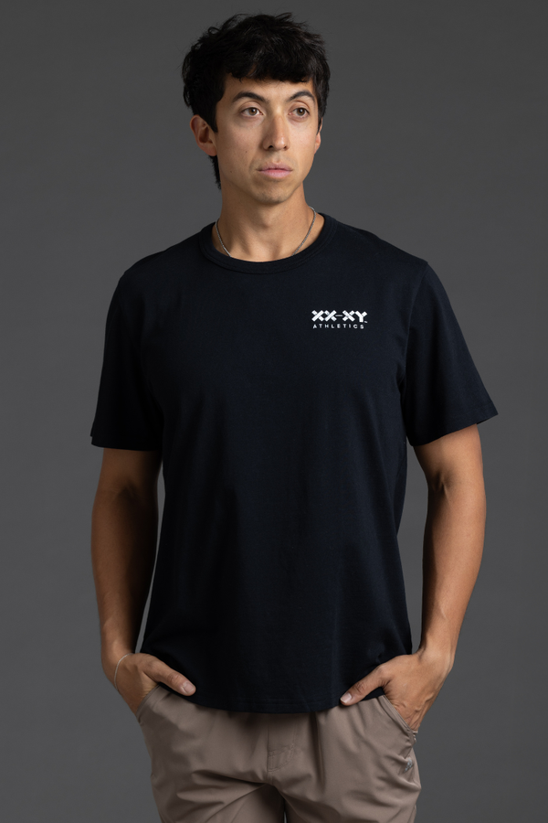 Person wearing a black t-shirt with a logo on a gray background || Black