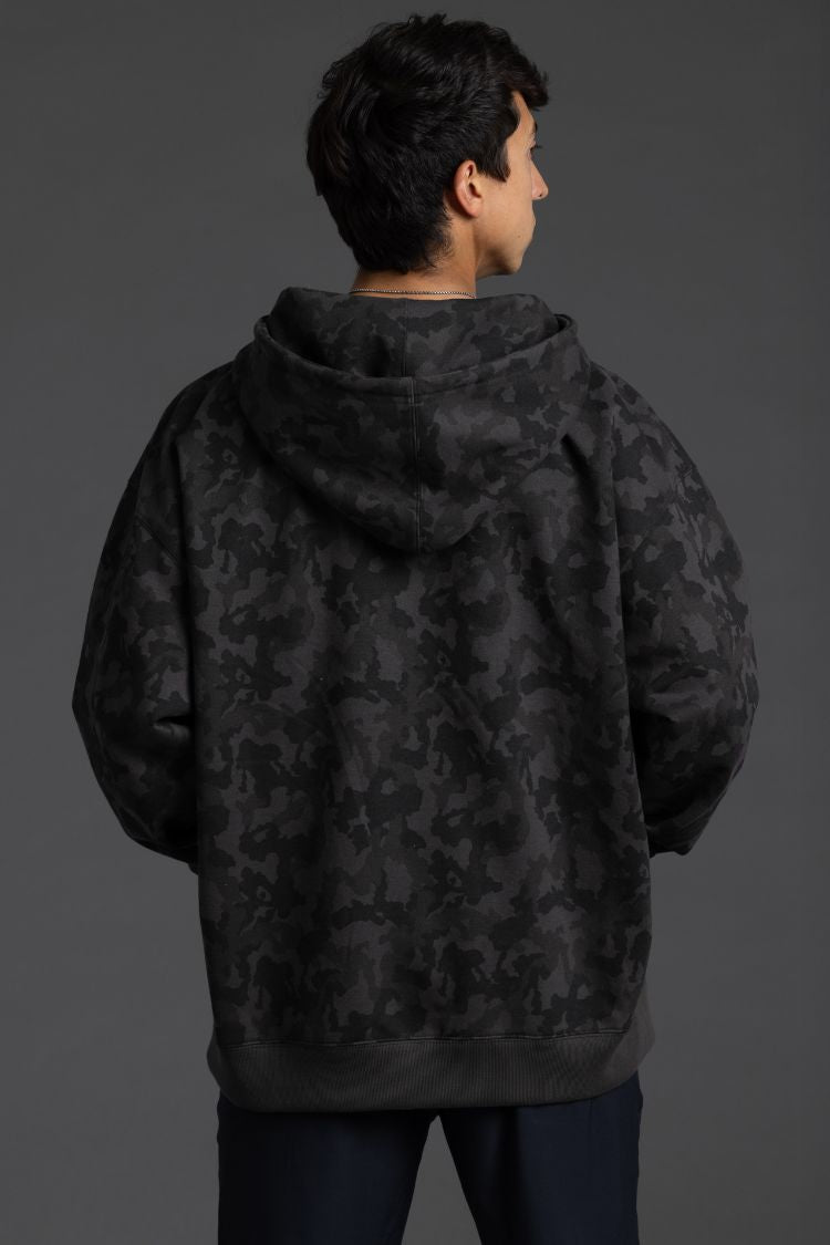 Person wearing a black camouflage hoodie against a gray background || Black Camo