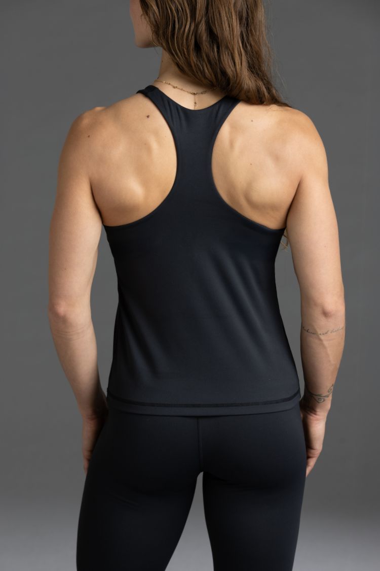 Person wearing a black tank top and leggings on a gray background || Black