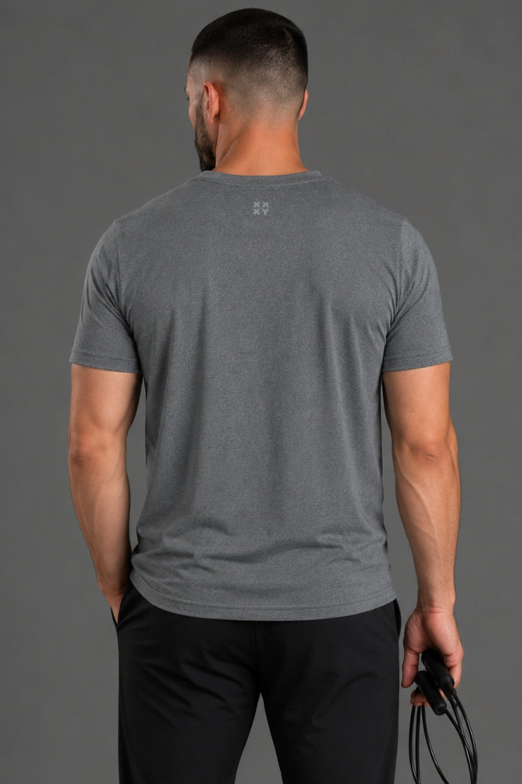 Man wearing a gray t-shirt with a small logo on the back against a gray background || Dark Heather Gray