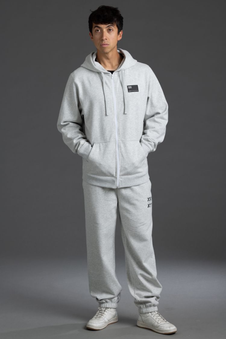 Person wearing a gray tracksuit with a logo on a gray background || Light Heather Gray