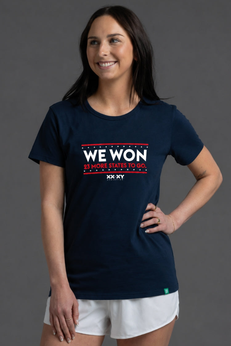 Woman wearing a navy blue t-shirt with 'WE WON 25 MORE STATES TO GO' text on a gray background