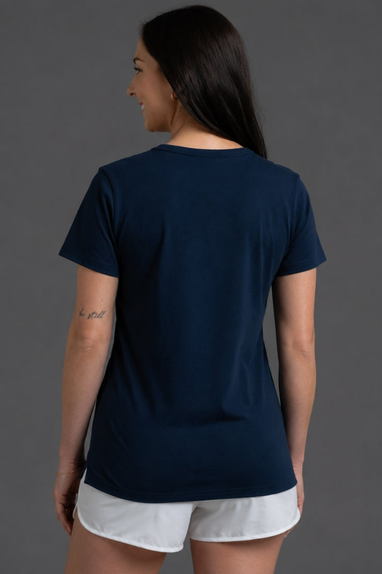 Woman wearing a navy blue t-shirt and white shorts on a gray background || Navy