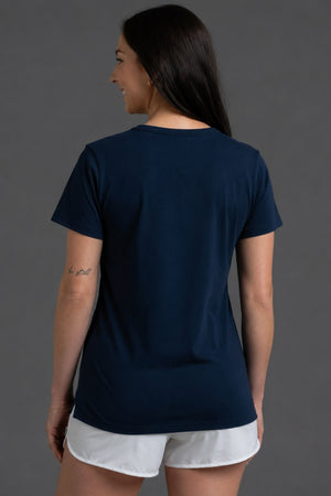 Woman wearing a navy blue t-shirt and white shorts on a gray background || Navy