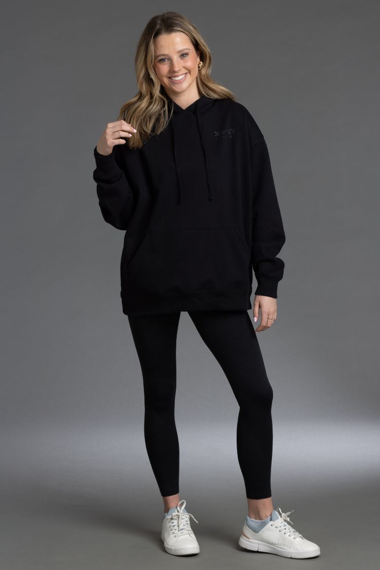 Woman wearing a black hoodie and leggings with white sneakers || Black - Back Graphic