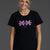 Woman wearing a black t-shirt with pink graphics and text on a gray background || Bright Fuchsia