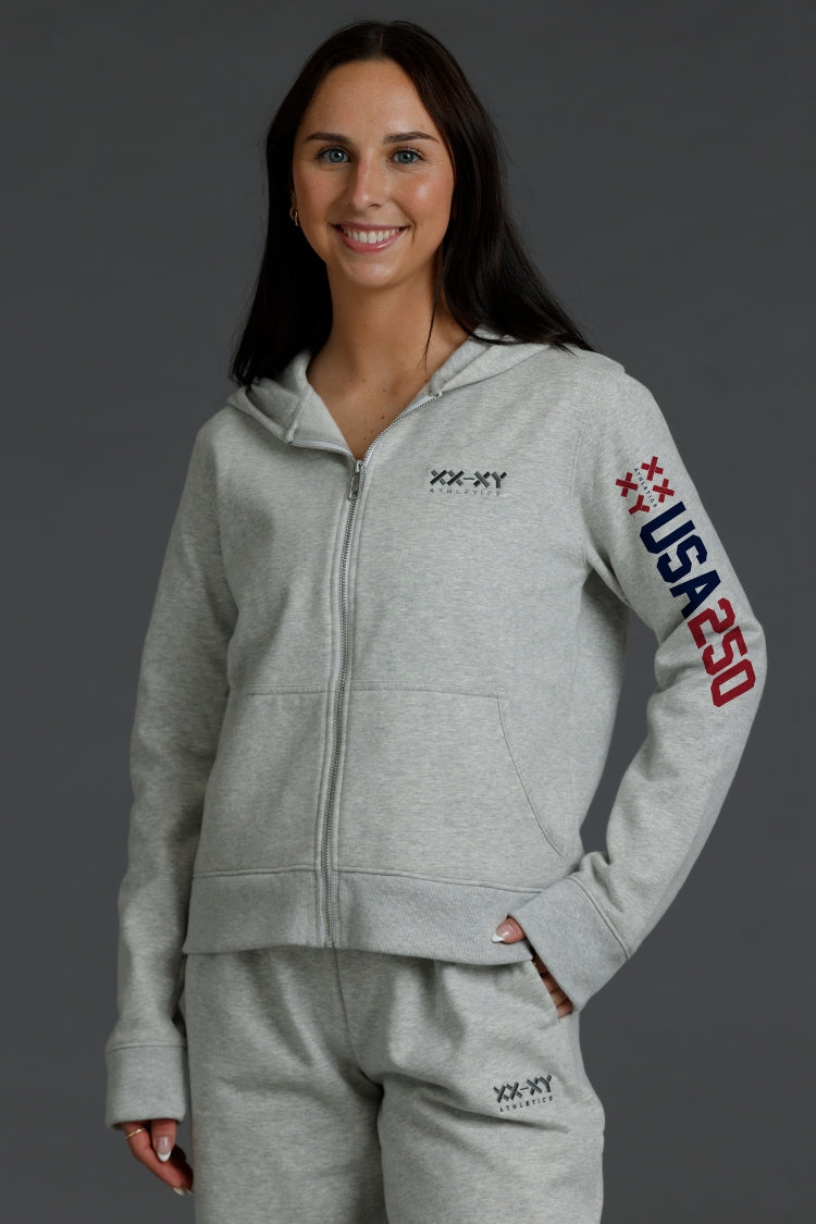 Woman wearing a gray hoodie with 'USA 250' text on a dark background || Light Heather Gray