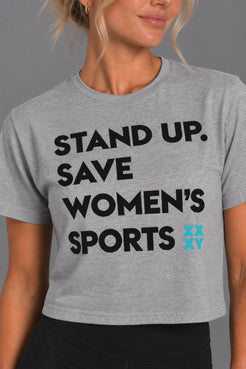 Blonde woman modeling the gray cropped Stand Up Save Women’s Sports graphic tee || Heather Gray