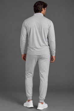 Back view of a male model wearing a light gray quarter-zip pullover with matching gray joggers and white sneakers against a gray studio background. || Light Heather Gray - 1