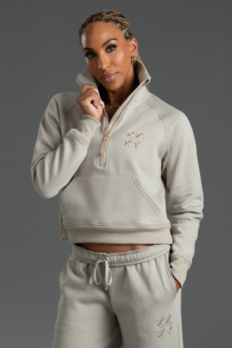 Woman wearing a Taupe tracksuit with a brand logo on a gray background ||  Taupe