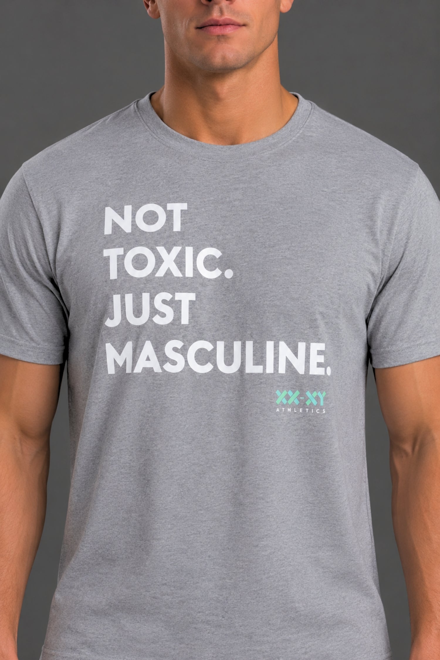 A man wearing a heather gray crewneck t-shirt with the text 'NOT TOXIC. JUST MASCULINE.