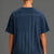 A woman viewed from the back wearing a navy blue t-shirt with a distressed American flag graphic and the words 'SAVE WOMEN'S SPORTS' printed across the upper back. || Navy