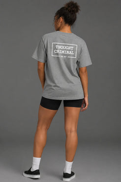 Black female model wearing a boyfriend-fit gray Thought Criminal graphic tee with black bike shorts. || Heather Gray