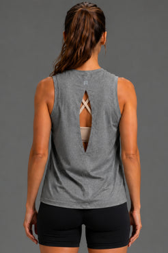 Rear view of a woman wearing a heather gray sleeveless athletic tank top with a cutout back design and black fitted shorts against a solid gray studio background. || Dark Heather Gray