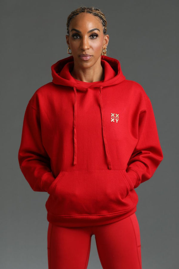 Person wearing a red hoodie with a logo on a gray background || red