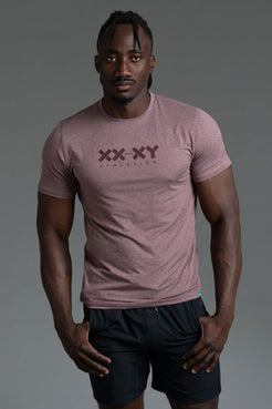 Man wearing a pink t-shirt with a logo on a gray background || Burgundy Heather