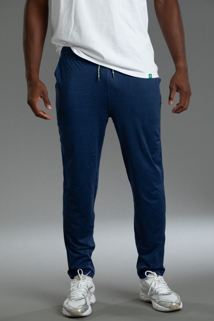 Person wearing navy blue jogger pants and white sneakers on a gray background || Navy
