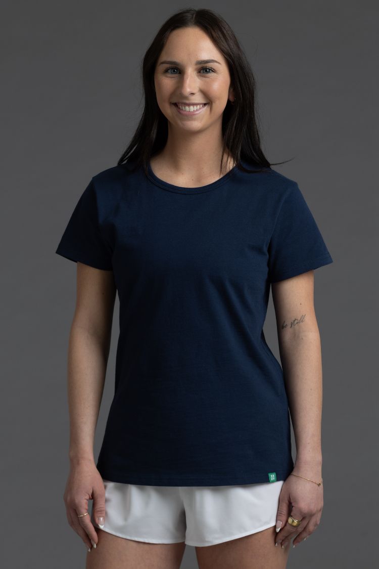 Woman wearing a navy blue t-shirt and white shorts on a gray background