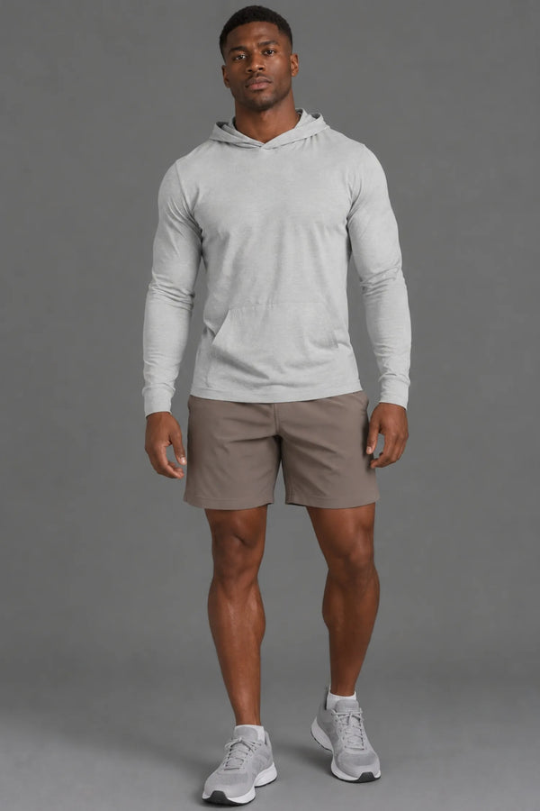 Black male model wearing a light gray performance hoodie with brown athletic shorts, ankle socks, and gray sneakers. || Light Heather Gray - 1
