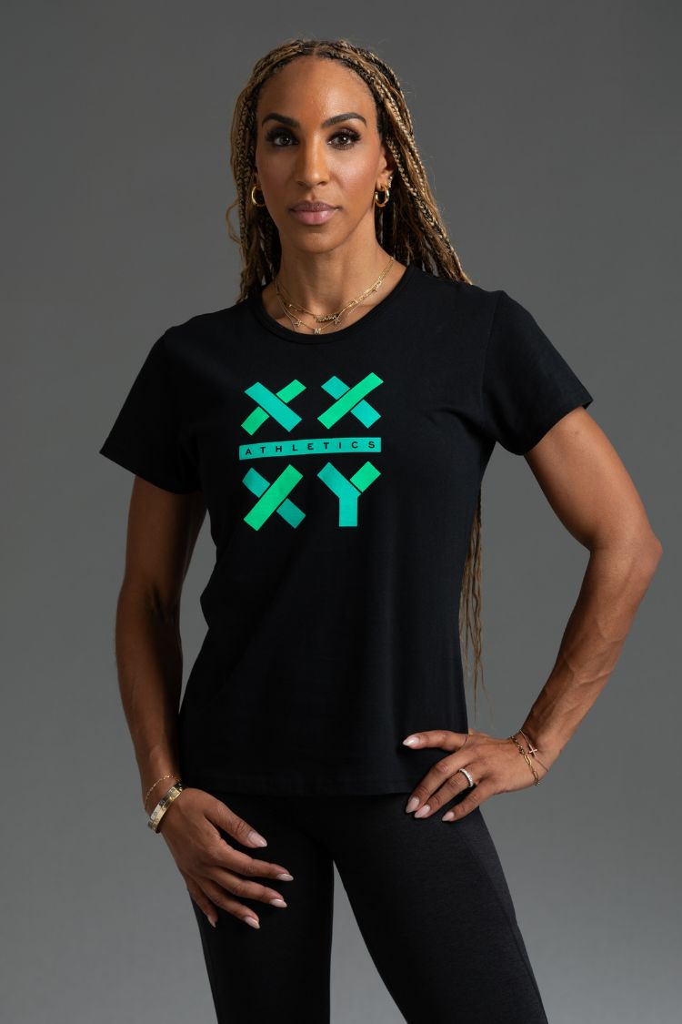 Woman wearing a black t-shirt with green graphics on a gray background || Black