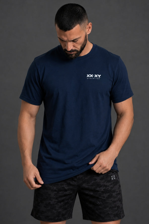 Man wearing a navy blue t-shirt with a logo on a gray background || Navy