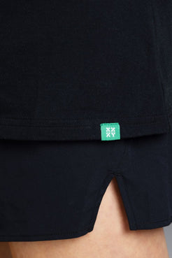 Close-up of a black garment with a green tag on a neutral background || Bright Fuchsia