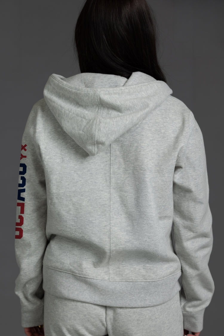 Person wearing a gray hoodie with colorful text on the sleeve against a dark background