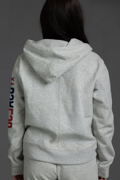 Person wearing a gray hoodie with colorful text on the sleeve against a dark background || Light Heather Gray