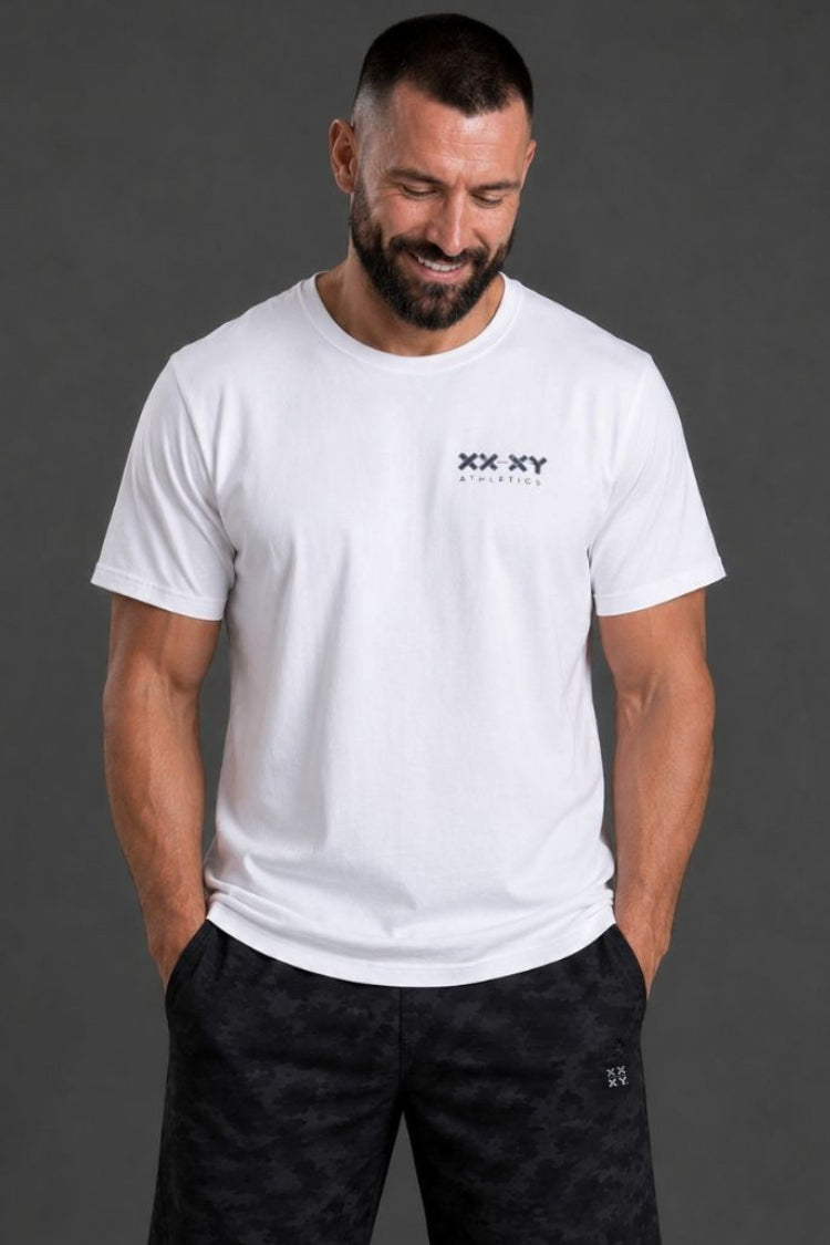 Man wearing a white t-shirt and black shorts with brand logos on a gray background