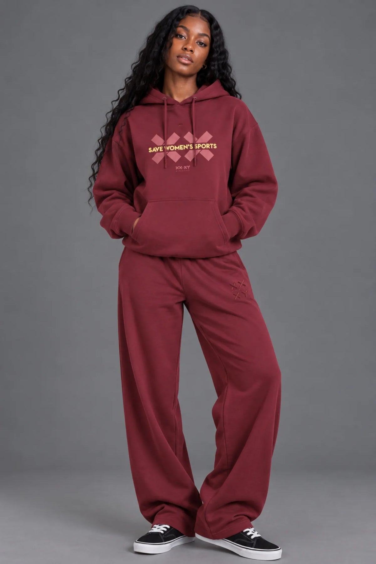 Black woman wearing a burgundy Save Women’s Sports hoodie with matching XX-XY Athletics sweatpants. || Red Wine