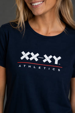 A close-up of a woman wearing a navy blue t-shirt with a white and red 'XX-XY Athletics' logo printed on the chest. || Navy