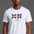 A man wearing a white short-sleeve t-shirt with a navy blue and red graphic on the chest that reads 'SAVE WOMEN'S SPORTS' and 'XX-XY FASHION', paired with red shorts, against a solid gray studio background. || White