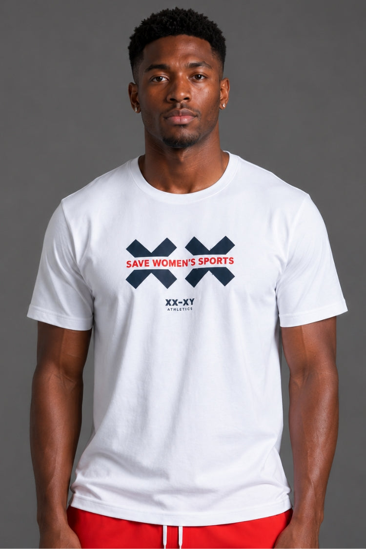 A man wearing a white short-sleeve t-shirt with a navy blue and red graphic on the chest that reads 'SAVE WOMEN'S SPORTS' and 'XX-XY FASHION', paired with red shorts, against a solid gray studio background. || White