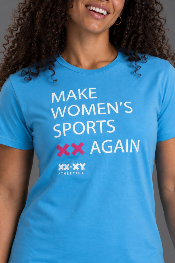 A woman wearing a bright blue graphic t-shirt with the text 'MAKE WOMEN'S SPORTS XX AGAIN' and the 'XXX-XY Athletics' logo printed on the front. || Light Blue