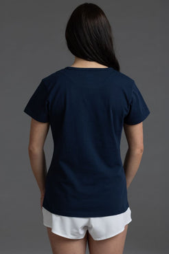 Person wearing a navy blue t-shirt and white shorts on a gray background || Navy