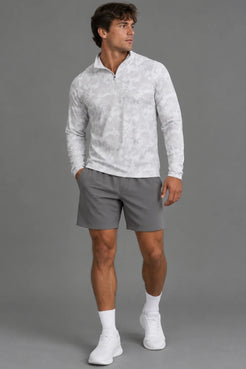 Male model wearing a white camo quarter-zip pullover with gray athletic shorts, white socks, and white sneakers. || White Camo