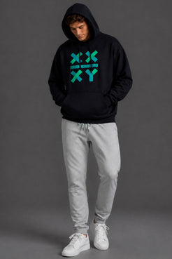 A man wearing a black pullover hoodie with a teal geometric 'XY' graphic on the chest, paired with light gray sweatpants and white sneakers, standing against a dark gray studio background. || Black with Color Logo