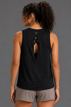 A woman shown from the back wearing a black sleeveless athletic tank top with a cutout and crisscross detail at the back, paired with taupe shorts, against a solid gray studio background. || Black
