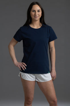 Woman wearing a navy blue t-shirt and white shorts against a gray background || Navy