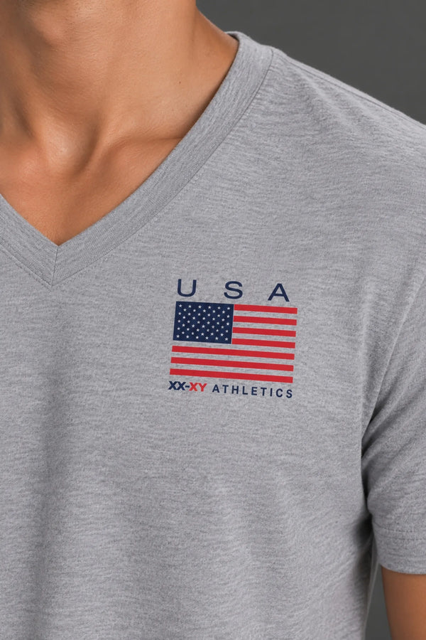 Close-up of the USA flag graphic and XX-XY Athletics logo printed on the chest of a heather gray V-neck T-shirt. || Light Heather Gray