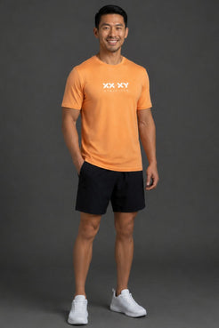 Man wearing an orange t-shirt with a logo and black shorts on a gray background || Light Orange