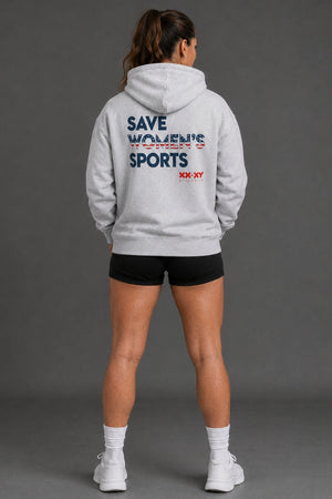 A woman viewed from behind wearing a light gray hoodie with 'SAVE WOLVES BY EXPRESS' and 'XX-XY' printed in navy and red on the back, paired with black athletic shorts, white socks, and white sneakers against a dark gray studio background. || Heather Gray