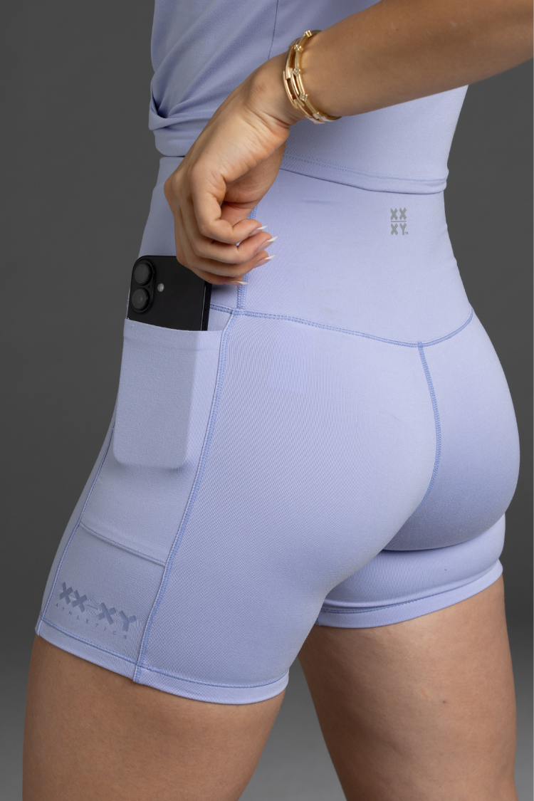 Lavender athletic shorts with a brand logo on a gray background